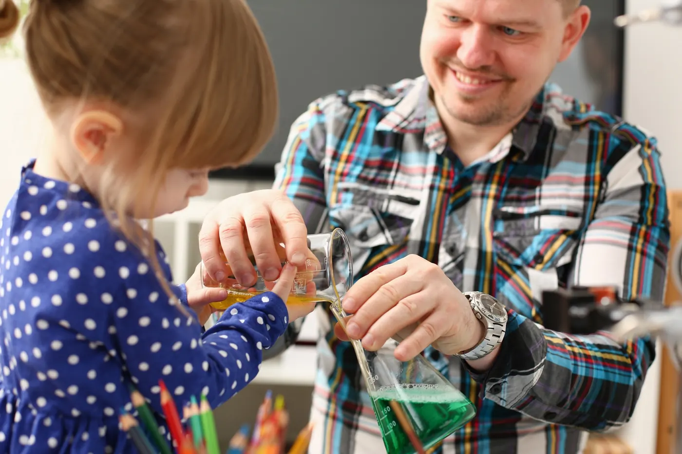 Ein Kind und ein Erwachsener experimentieren mit bunten Flüssigkeiten
