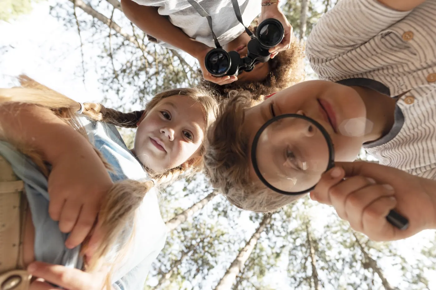 Kinder erkunden gemeinsam ihre Umgebung mit Lupe und Fernglas